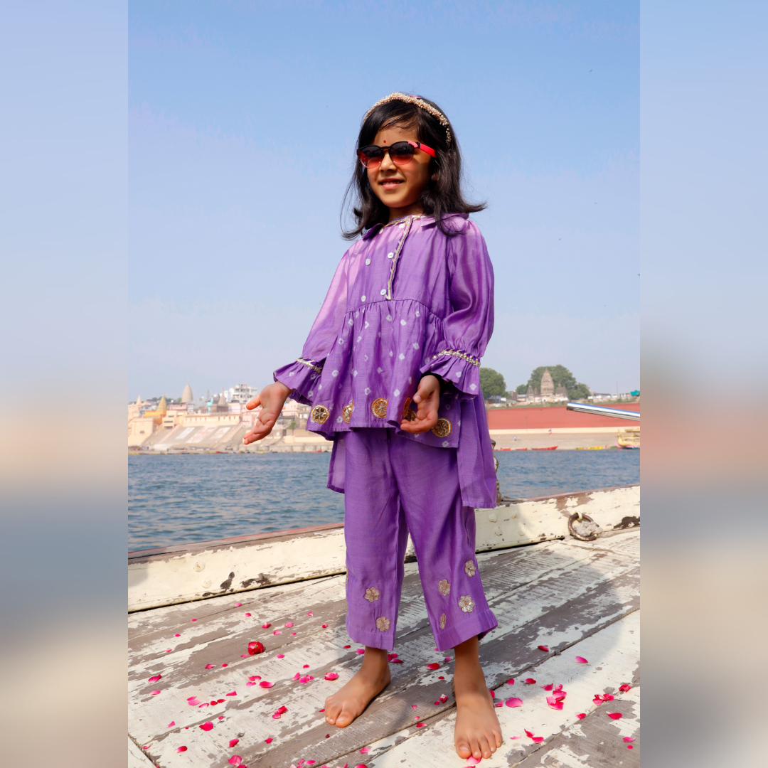 Young girl in a lilac coord set with gota lace and flowers.